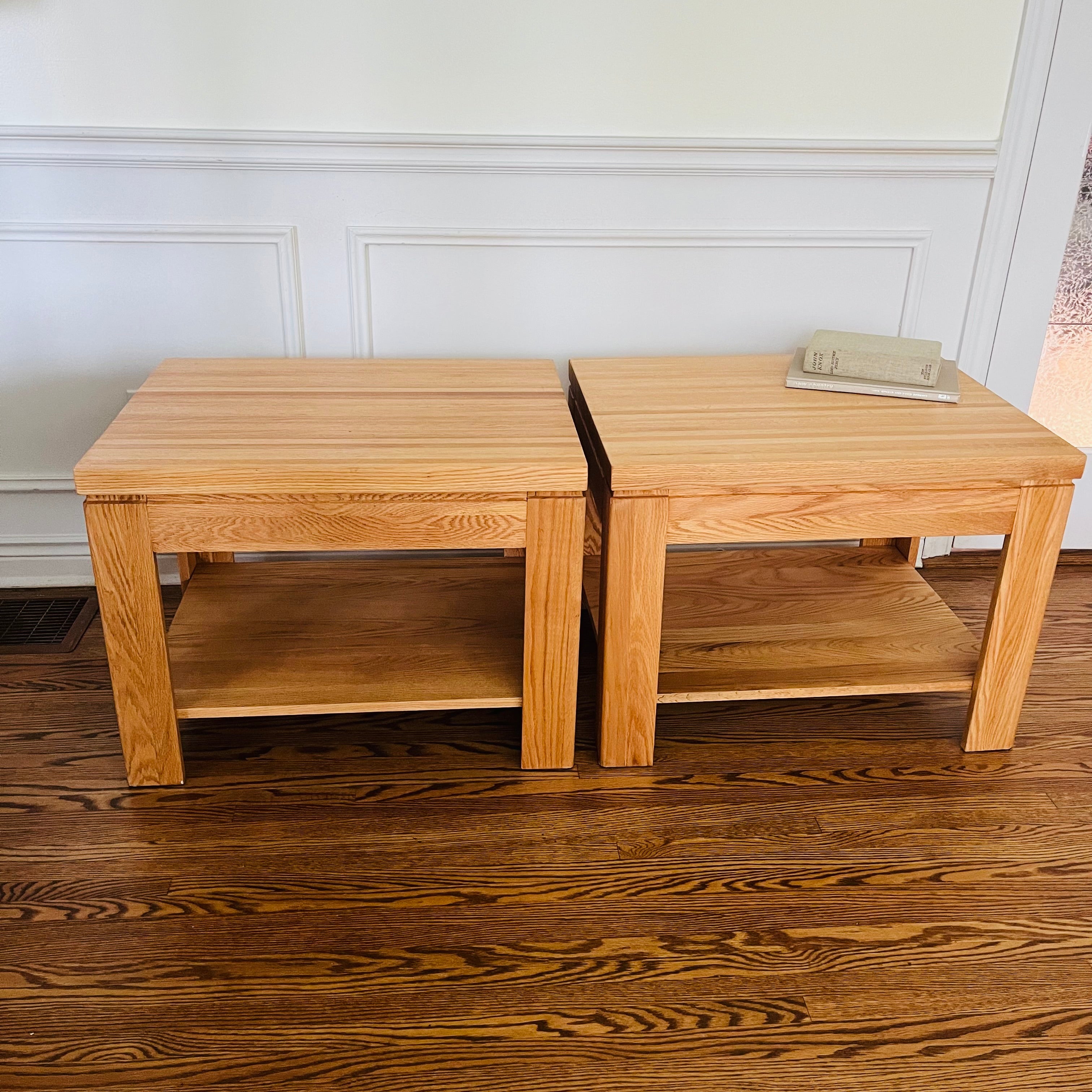 Pair of solid oak end tables with a clean, sturdy profile and practical lower shelves.