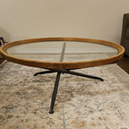 Round wooden coffee table with glass top on a patterned rug